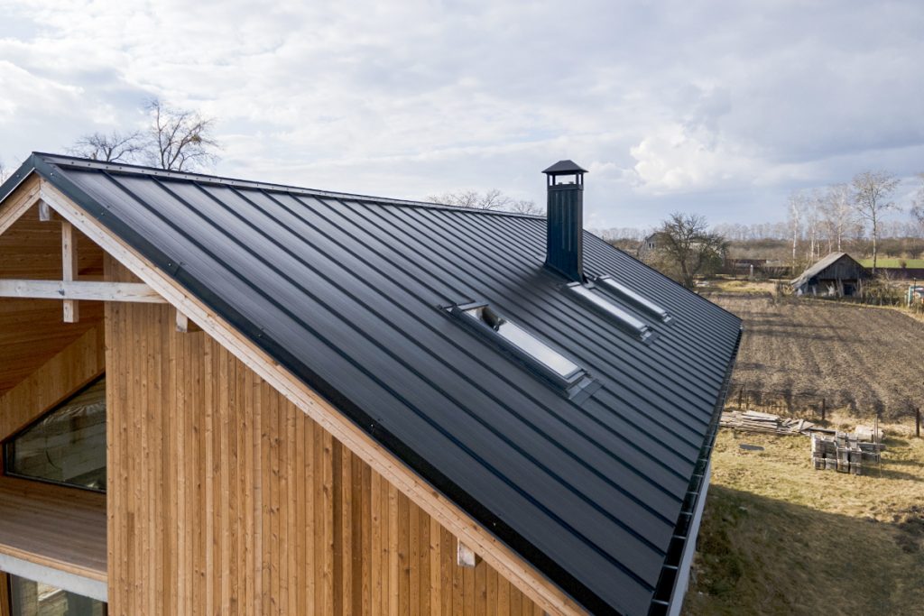 Nowoczesne pokrycie dachowe z blachy na drewnianej konstrukcji domu, podkreślające ważność izolacji w architekturze dachowej.